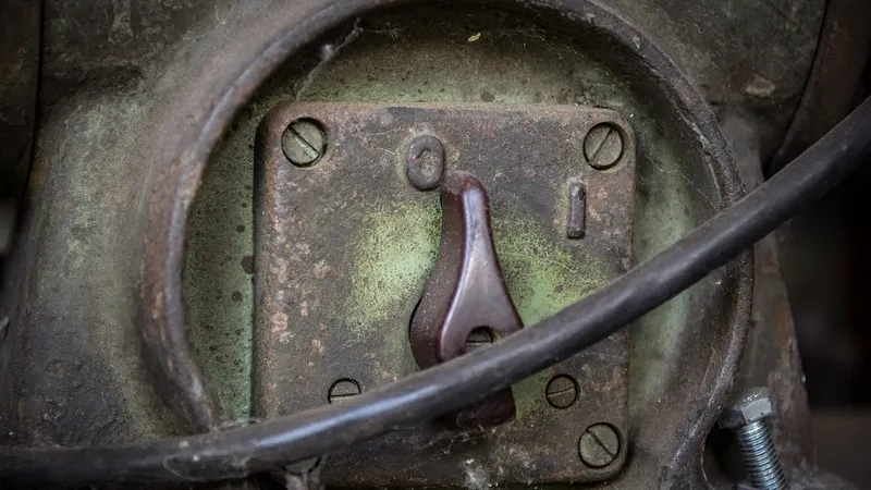 A single lever in low light — a switch held open by a signal, ready to fire the moment it goes quiet.