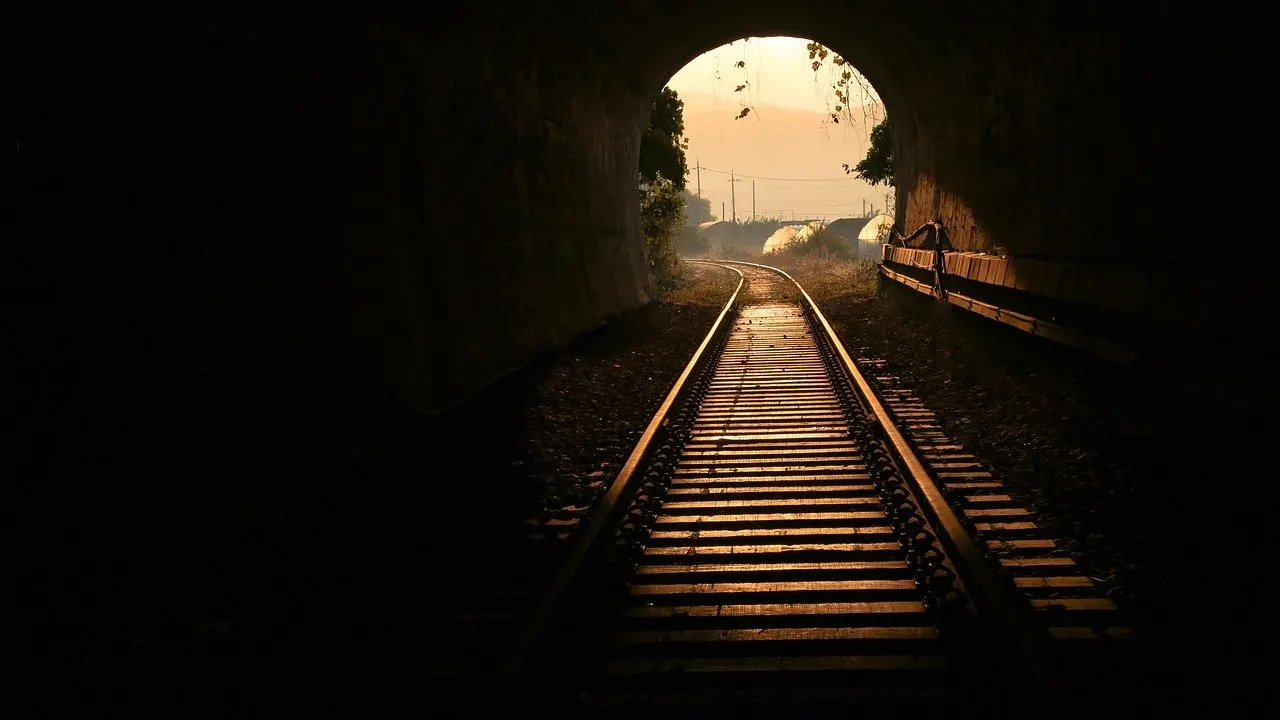 A dark rail track vanishing into low light — an idle service put to sleep between requests.
