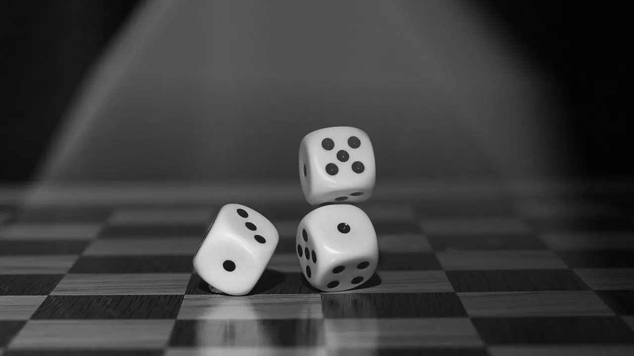 Dice on a board in low light — the same event landing more than once, each doing the work again.