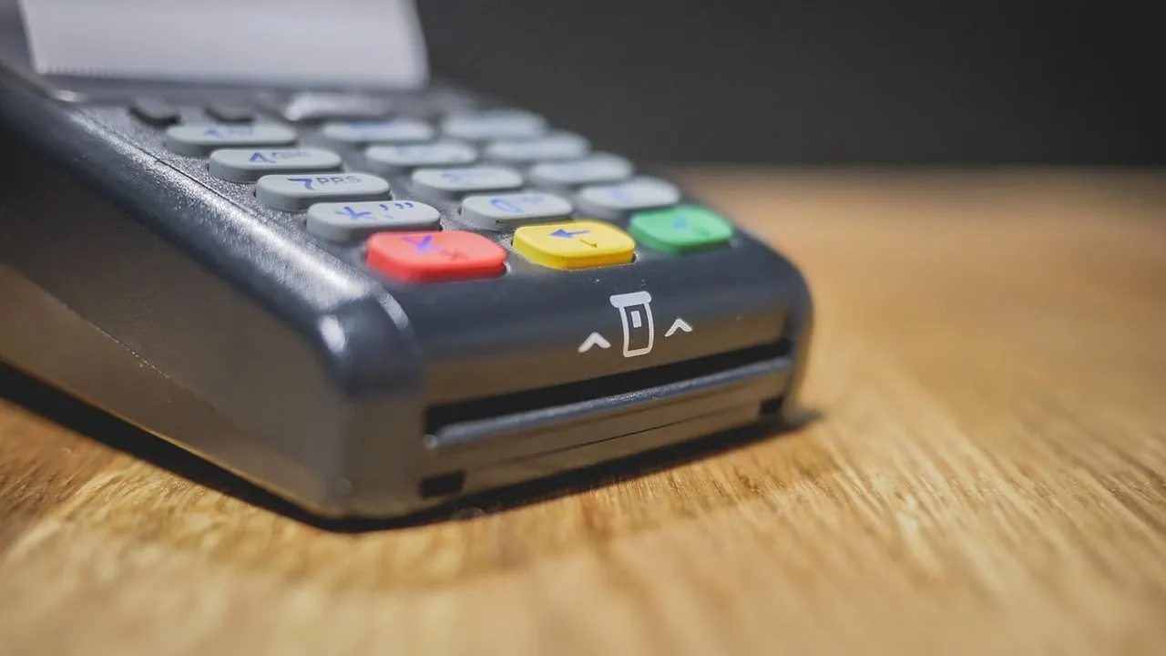 A card payment terminal on a dark counter — a charge that went through while the app never heard about it.