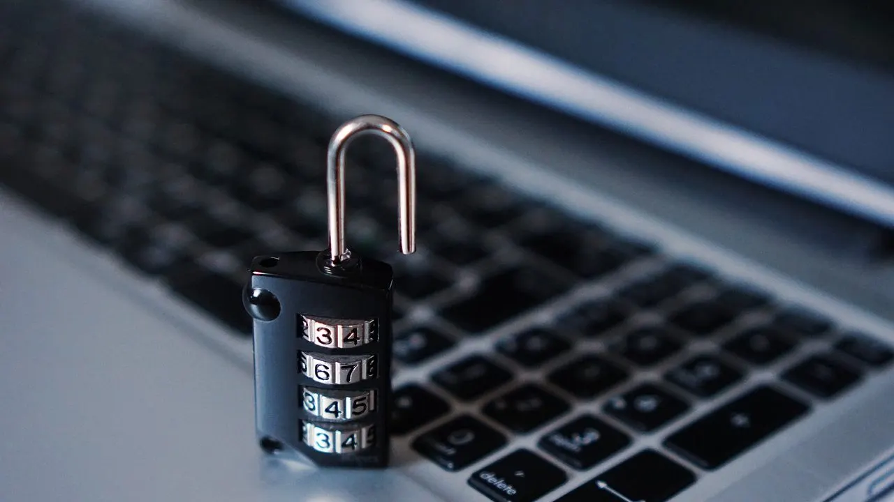 An unlocked padlock resting on a laptop keyboard in low light — an app shipped without its defenses set.